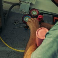 A technician using an A/C manifold gauge set on a vehicle