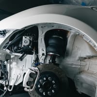 A car's structural chassis and suspension exposed with the fender removed
