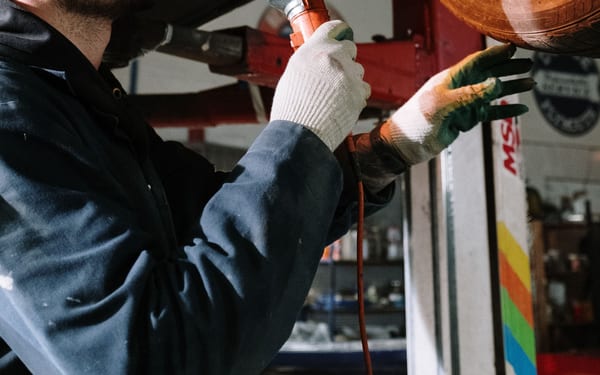 A mechanic inspecting the underside of a car with a flashlight