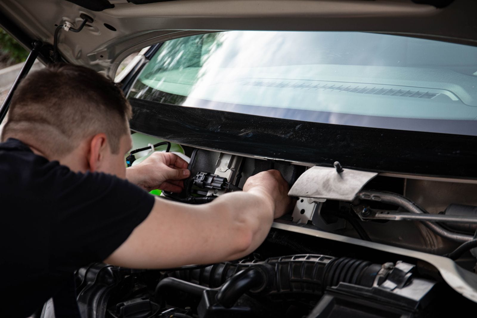 A mechanic working inside an open vehicle engine bay