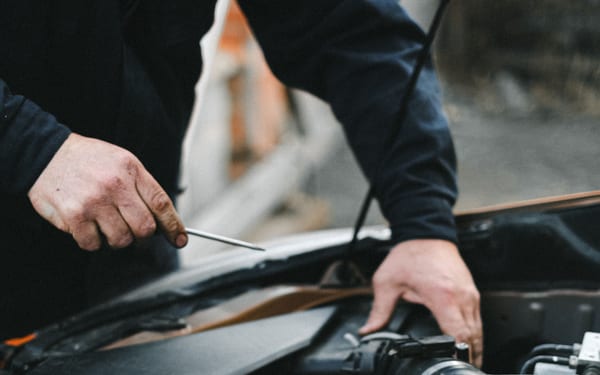 A mechanic's hands working under an open car hood