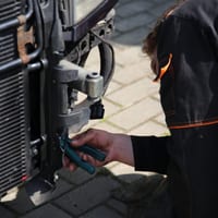A mechanic working directly on a car radiator