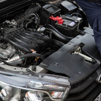 A mechanic examining an open car engine bay