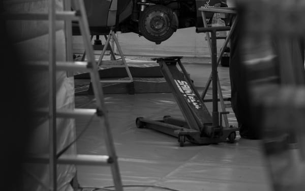 A black-and-white photo of a car's suspension in a garage